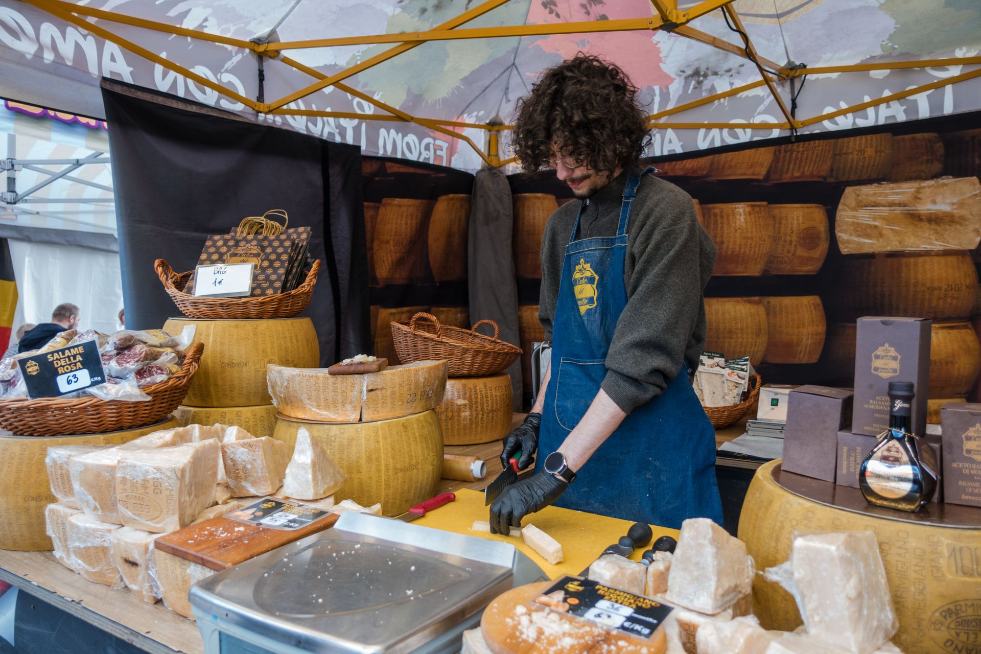 Fromager coupant du fromage sur un étal de marché en plein air